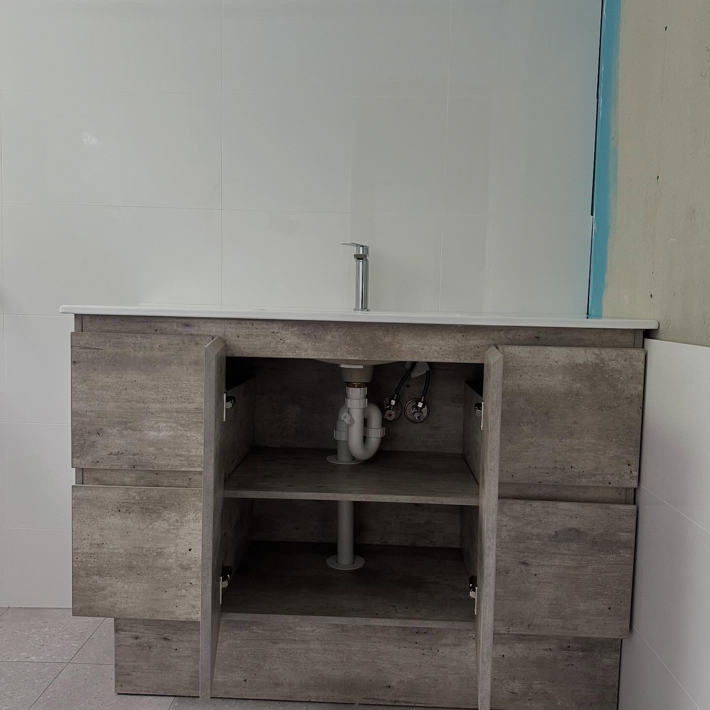 New vanity with the cupboard doors open, showing the plumbing underneath